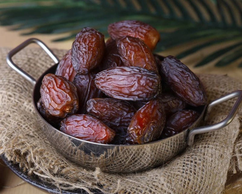 Metal bowl filled with medjool dates on a rustic background