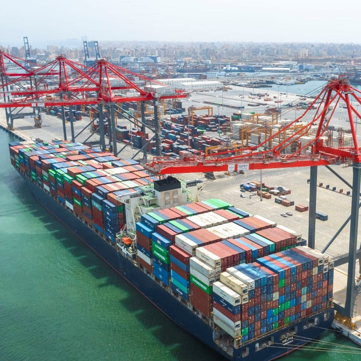Container ship docked at a port with cranes and shipping containers.