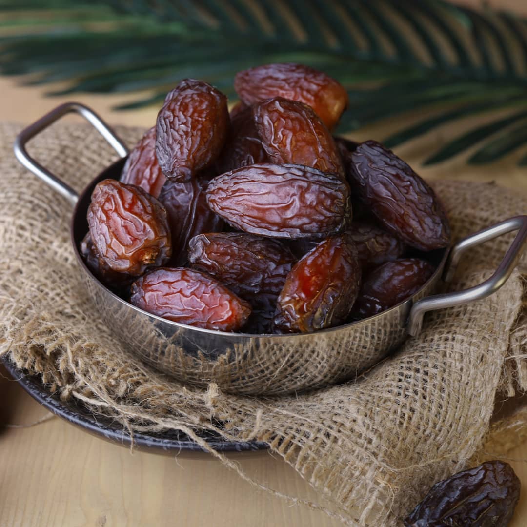 Metal bowl filled with medjool dates on a rustic background